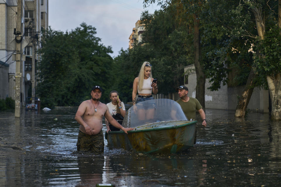 Rescue workers attempt to tow boats carrying residents being evacuated from a flooded neighborhood in Kherson, Ukraine, Tuesday, June 6, 2023. The wall of a major dam in a part of southern Ukraine has collapsed, triggering floods, endangering Europe's largest nuclear power plant and threatening drinking water supplies. (AP Photo/Libkos)