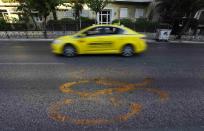 A taxi drives by fading Olympic rings which mark the Olympic Traffic Lane on an avenue leading to the Athens 2004 Olympic Complex in Athens July 26, 2014. Ten years after Greece hosted the world's greatest sporting extravaganza, many of its once-gleaming Olympic venues have been abandoned while others are used occasionally for non-sporting events such as conferences and weddings. For many Greeks who swelled with pride at the time, the Olympics are now a source of anger as the country struggles through a six-year depression, record unemployment, homelessness and poverty. Just days before the anniversary of the Aug. 13-29 Games in 2004, many question how Greece, among the smallest countries to ever host the Games, has benefited from the multi-billion dollar event. Picture taken July 26, 2014. REUTERS/Yannis Behrakis (GREECE - Tags: BUSINESS POLITICS SPORT TRANSPORT) ATTENTION EDITORS: PICTURE 25 OF 33 FOR WIDER IMAGE PACKAGE 'TEN YEARS ON - ATHENS' FADING OLYMPIC STADIUMS' TO FIND ALL IMAGES SEARCH 'BEHRAKIS KARAHALIS'
