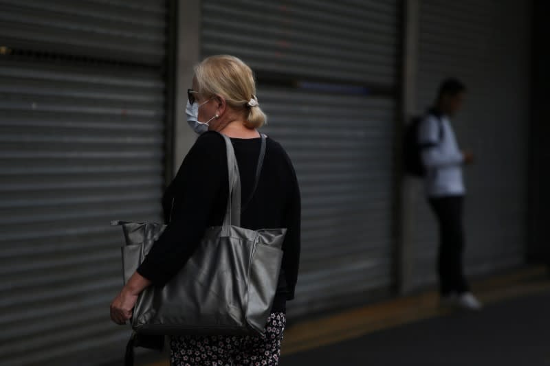 A woman wearing a face mask stands in front a closed mall that reduced its opening hours amid the coronavirus disease (COVID-19) outbreak in Sao Paulo