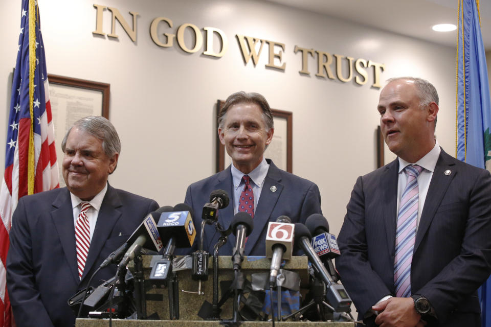 Oklahoma Attorney General Mike Hunter, center, smiles as he answers a question during a news conference following the announcement of the Opioid Lawsuit decision in Norman, Okla., Monday, Aug. 26, 2019. With him are state's attorneys Michael Burrage, left, and Brad Beckworth, right. (AP Photo/Sue Ogrocki)