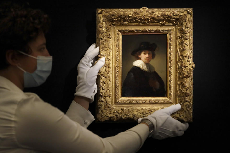 FILE - In this Thursday, July 23, 2020 file photo, a Sotheby's employee adjusts a painting by Rembrandt, entitled 'Self-portrait, wearing a ruff and black hat' at Sotheby's auction rooms in London. The auction house Sotheby’s is holding an online sale featuring artwork that spans five centuries of art history, from Rembrandt to Pablo Picasso and Joan Miró to Banksy. The auction on Tuesday, July 28, 2020, of 70 artworks, from the 17th century to the present day, will be live-streamed from Sotheby's London. The event comes after months of disruption to the art world due to the coronavirus outbreak. (AP Photo/Kirsty Wigglesworth, File)