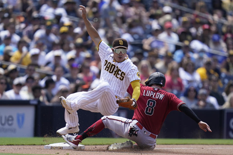 San Diego Padres third baseman Ha-Seong Kim, left, falls over Arizona Diamondbacks' Jordan Luplow (8) after tagging him out on a fielder's choice by Jake Hager during the fourth inning of a baseball game Wednesday, June 22, 2022, in San Diego. Hager was safe at first on the play. (AP Photo/Gregory Bull)