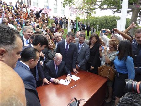 California Governor Jerry Brown (C) is surrounded by state and local officials after he signed AB60 into law during ceremonies in Los Angeles October 3, 2013. REUTERS/Office of Mayor Eric Garcetti/Handout via Reuters