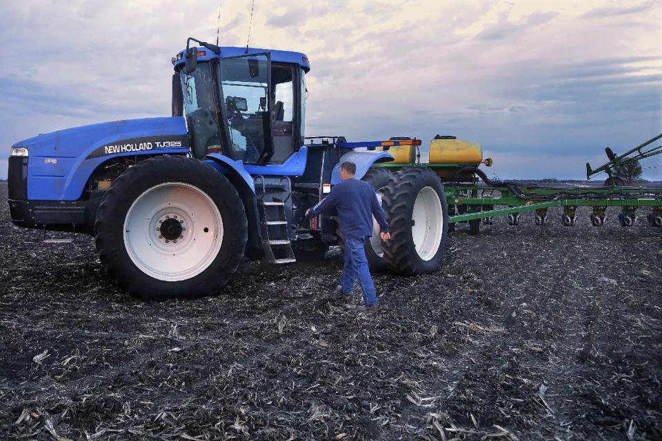 In this Saturday, May 3, 2014 photo, central Illinois corn and soybean farmer Michael Mahoney walks back to his tractor to continue planting seed corn into the evening in Ashland, Ill. A U.S. government report says the nation's corn growers should have banner production this year despite lesser acreage devoted to the grain. But corn prices later in the year may suffer a bit. (AP Photo/Seth Perlman)