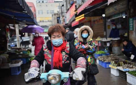 Locals in Wuhan are wearing masks to protect themselves - Credit: Hector Retamal/AFP