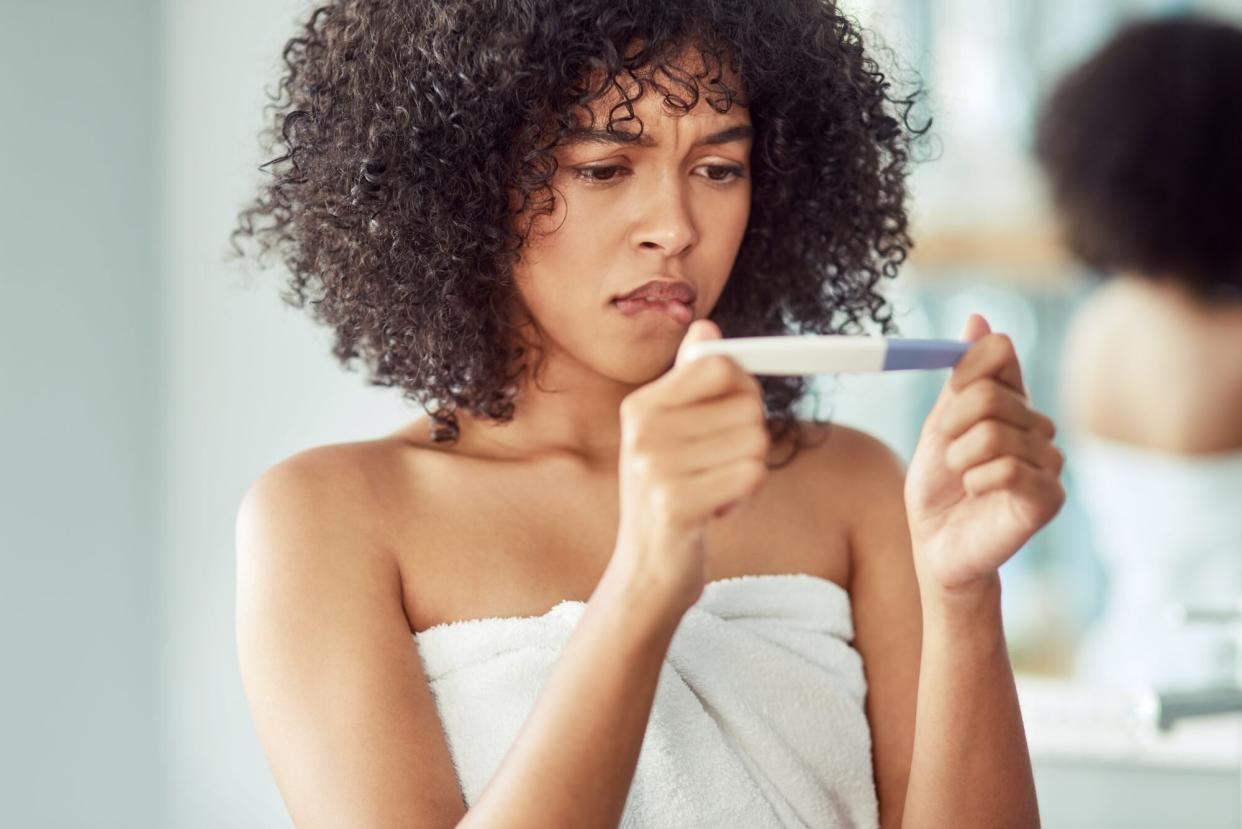 young woman looking upset after taking a pregnancy test