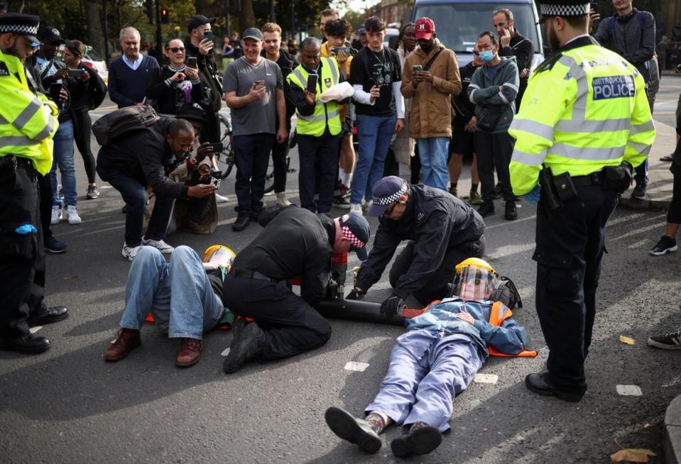 29 octobre 2022 : Des membres du public prennent des photos alors que des policiers retirent des militants d'une route lors d'une manifestation « Just Stop Oil », à Londres (Reuters)