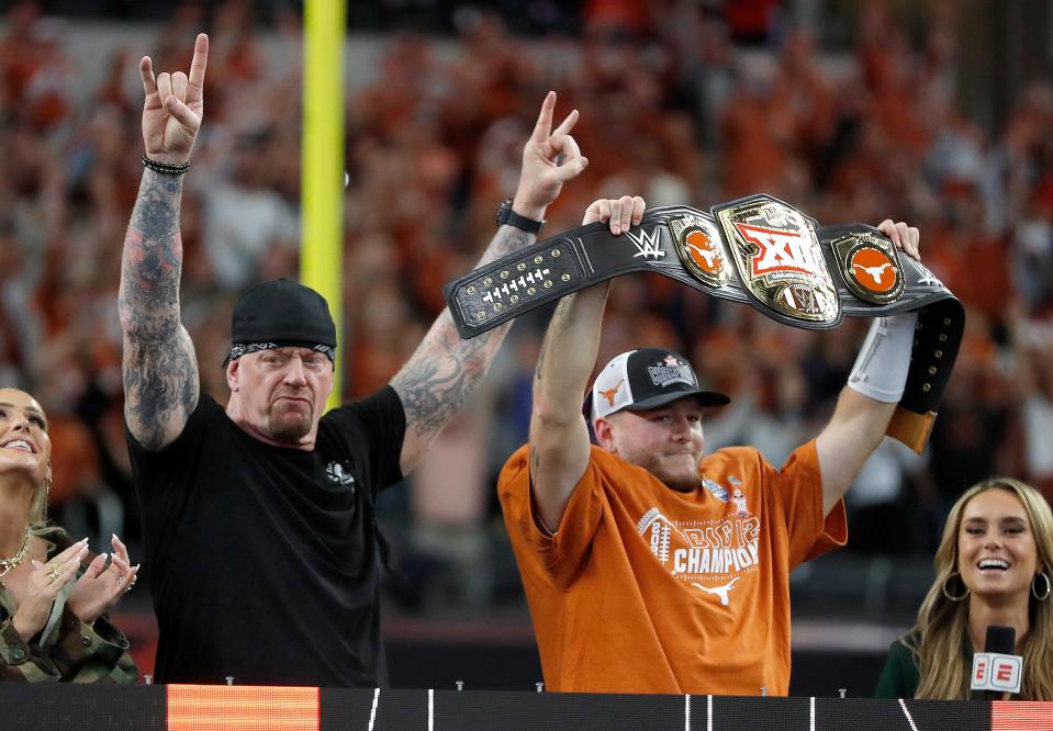 Texas's Quinn Ewers holds up the WWE Big 12 Championship belt next to The Undertaker after the Longhorns beat Oklahoma State 49-21 on Saturday at AT&T Stadium in Arlington, Texas.