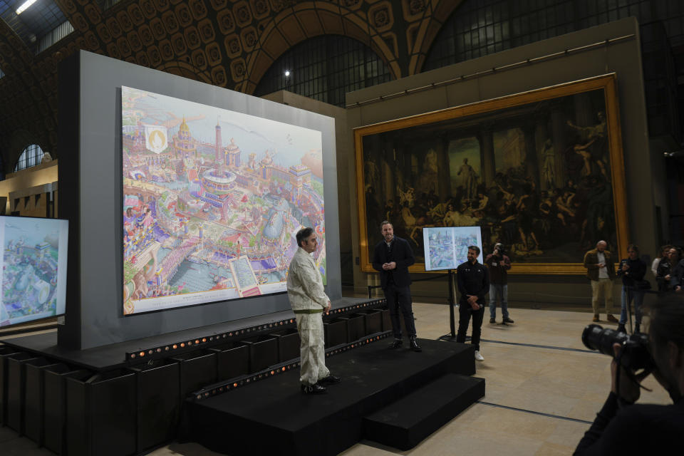 CORRECTS SPELLING OF FIRST NAME FROM HUGO TO UGO - French artist Ugo Gattoni, center, poses with the Paris 2024 Olympic and Paralympic posters at the Musee d'Orsay, in Paris, Monday, March 4, 2024. Vibrant colors and striking landmarks illuminate posters for the Paris Olympic Games in an Art Deco style inspired by the city's flamboyant past. (AP Photo/Thibault Camus)