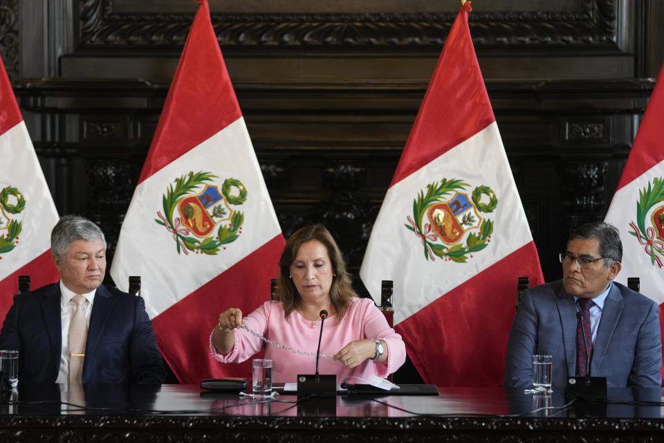 La presidenta de Perú, Dina Boluarte, muestra un collar, acompañada por sus abogados Mateo Castañeda, a la izquierda, y Eduardo Barriga, en una conferencia de prensa en la Palacio de gobierno en Lima, Perú, el viernes 5 de abril de 2024. La fiscalía investiga a la mandataria por presunto enriquecimiento ilícito por movimientos en dinero y el uso de relojes de lujo y joyas. (AP Foto/Martín Mejía)