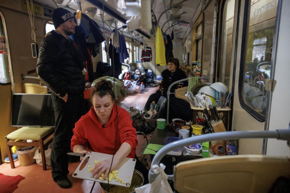 Lena Artyomenka, who has been sheltering in a metro station since the first day of the war, prepares food in a subway car where she currently lives (Reuters)