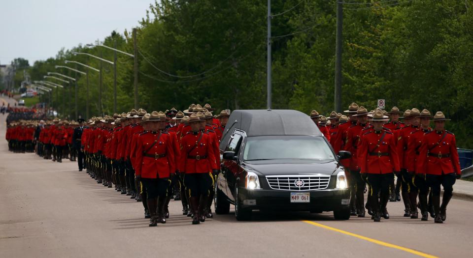 Royal Canadian Mounted Police officers march beside a hearse during a funeral procession for three fellow officers who were killed last week in Moncton