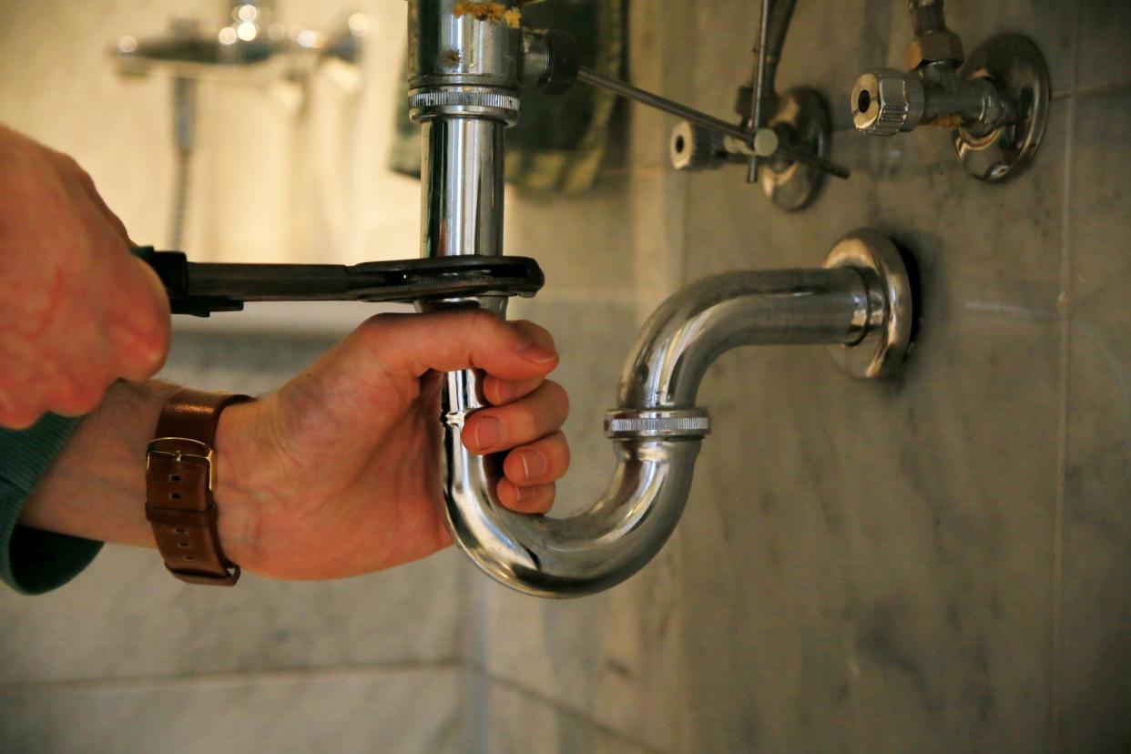 A handyman fixing the faucet of the bathroom with a wrench