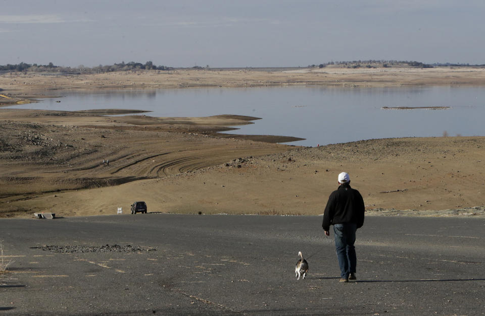 FILE -- In this Jan. 9, 2014 file photo a visitor to Folsom Lake, Calif., walks his dog down a boat ramp that is now several hundred yards away from the waters edge, in Folsom, Calif. Gov. Jerry Brown was governor the last time California had a drought of epic proportions, in 1975-76 and now is pushing a controversial $25 billion plan to build twin tunnels to ship water from the Sacramento-San Joaquin River Delta to farmland and cities further south. (AP Photo/Rich Pedroncelli,file)