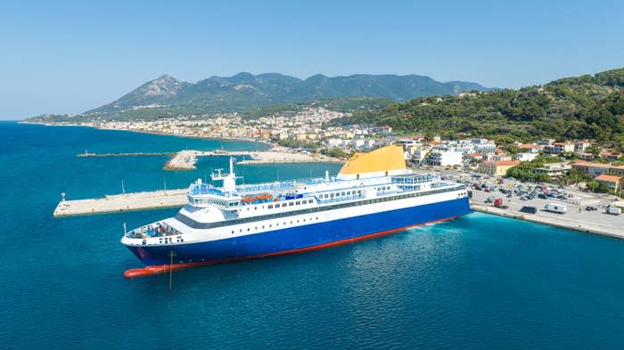 Large ferry docked at a coastal town with mountains in the background, showcasing maritime economy and tourism industry