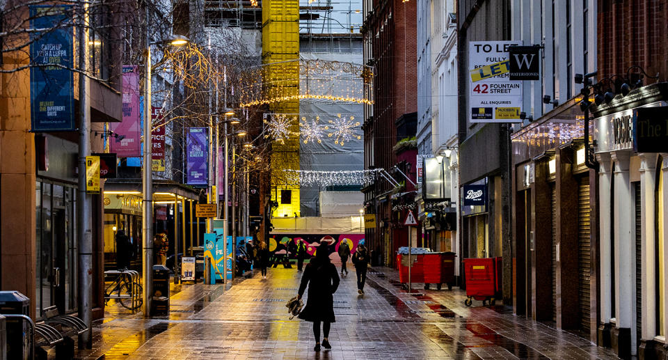 Person walking along a lit up street in Belfast. Source: AP