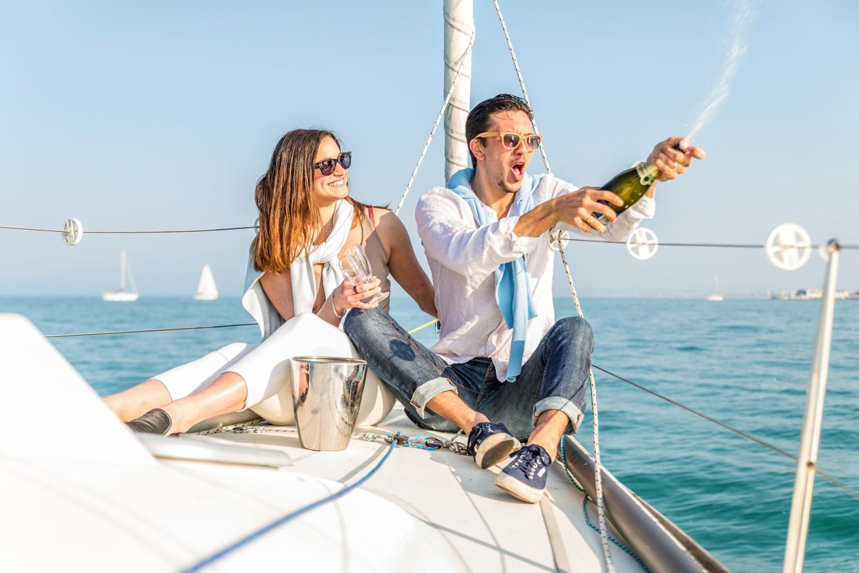 two young adults drinking champagne and having fun on a boat