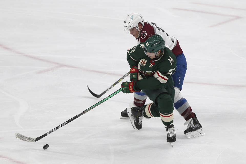 Minnesota Wild's Kevin Fiala (22) and Colorado Avalanche's Jacob MacDonald (34) go after the puck during the third period of an NHL hockey game Wednesday, April 7, 2021, in St. Paul, Minn. (AP Photo/Stacy Bengs)