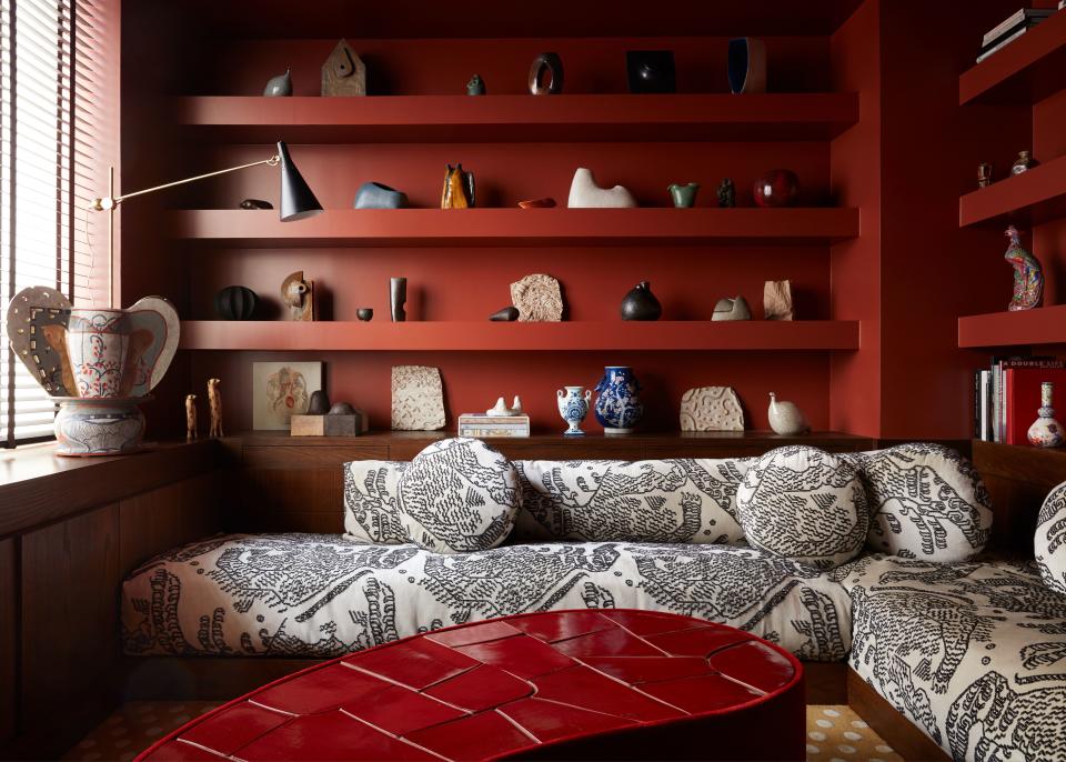 The apartment’s second bedroom was turned into a social space imbued with deep red hues. A custom sectional, upholstered in Dedar’s Tibetan-inspired “Tiger Silk,” hugs the room. The curvy coffee table designed by Valle has mohair siding and a ceramic top with hand-cut tiles made by Natalie Weinberger.