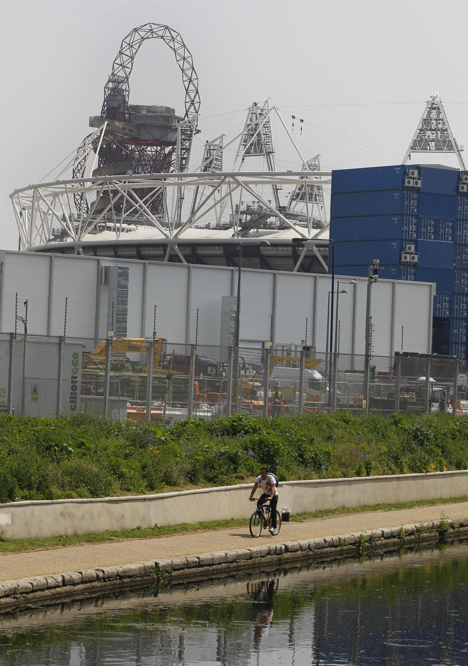 A cyclist passes by the Olympic Stadium and Orbit sculpture on a canal side cycle path in London, Thursday, May 24, 2012. There are many cycle paths across London that can be used to travel the capital. Like a runner or a swimmer, you would need to be physically fit. Like a goalie or a boxer, you should be prepared for close calls. But if you are coming to London's Summer Olympics _ and you have what it takes _ using a bicycle could be a great option in a city bracing for gridlock. (AP Photo/Kirsty Wigglesworth)