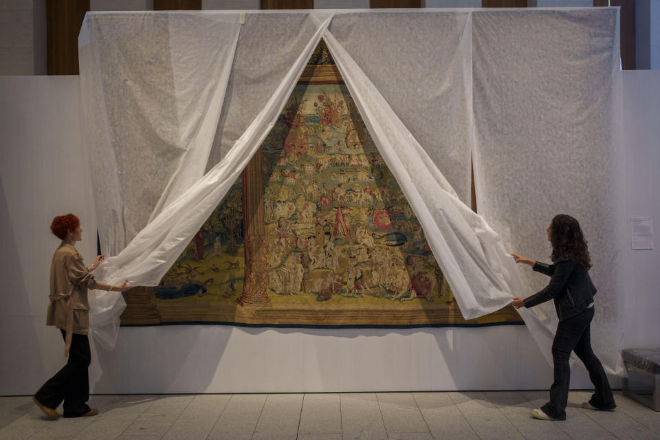 Staff members of the museum unveil a tapestry called "El jardin de las delicias" at the Royal Collections Gallery in Madrid, Spain, Friday, May. 19, 2023. Spain is set to unveil what is touted as one of Europe’s cultural highlights of the year with the opening in Madrid of The Royal Collections Gallery next month. The Gallery will feature master paintings, tapestries, sculptures, decorative art pieces, armory and sumptuous royal furniture collected by Spanish monarchs over five centuries that spanned the Spanish Empire of the Hapsburg and Bourbon dynasties. (AP Photo/Manu Fernandez)