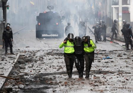 Riot police assist an injured colleague during protests after Ecuador's President Lenin Moreno's government ended four-decade-old fuel subsidies, in Quito