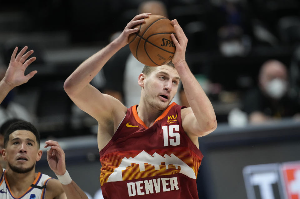 Denver Nuggets center Nikola Jokic, right, pulls in a rebound in front of Phoenix Suns guard Devin Booker in the first half of Game 4 of an NBA second-round playoff series Sunday, June 13, 2021, in Denver. (AP Photo/David Zalubowski)