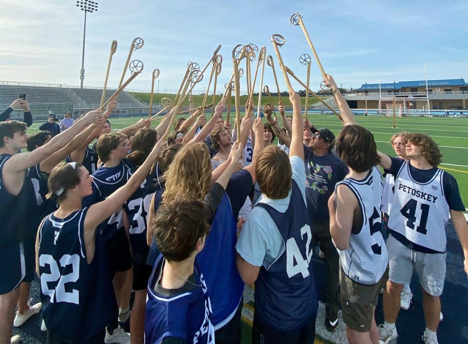 Members of the Petoskey lacrosse program hold up the Native American traditional sticks of the game after playing and getting a lesson on the Native sport recently at Northmen Stadium.