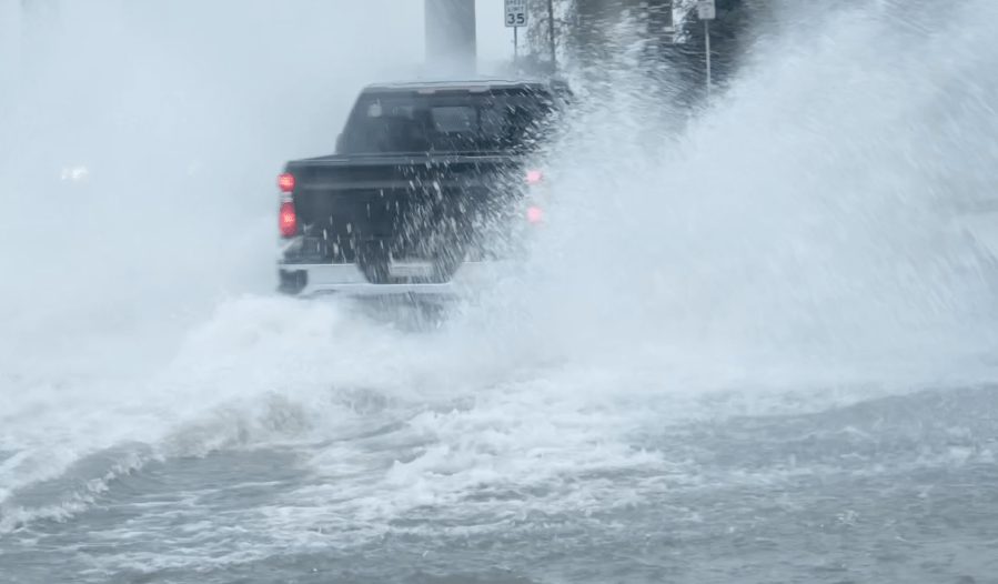 A pickup truck drives through a flooded area