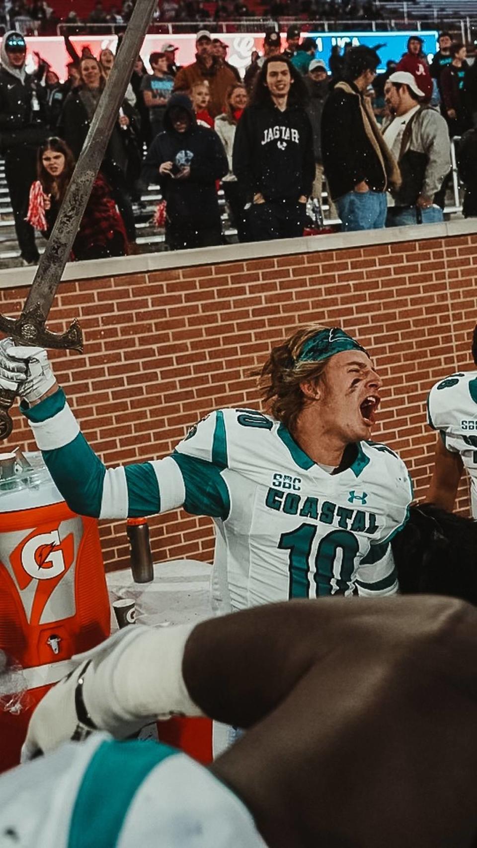 Following one of his two interceptions on Friday, Coastal Carolina safety Alex Spillum raises a sword that goes with CCU’s turnover cloak on the sideline at Hancock Whitney Stadium in Mobile, Ala. Nov. 26. 2021.