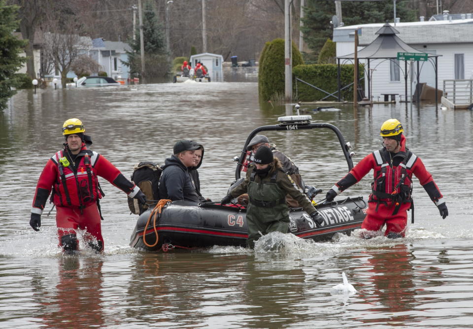 Rescue workers help evacuees retrieve some belongings from flooding from the Lake of Two Mountains, Wednesday, May 1, 2019, in Sainte-Marthe-sur-le-Lac, Quebec, Canada. (Ryan Remiorz/The Canadian Press via AP)