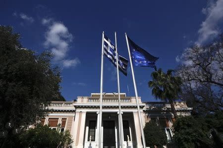 A Greek national flag (L) and a European Union flag wave outside the office of Greek Prime Minister Antonis Samaras in Athens June 9, 2014. REUTERS/Alkis Konstantinidis