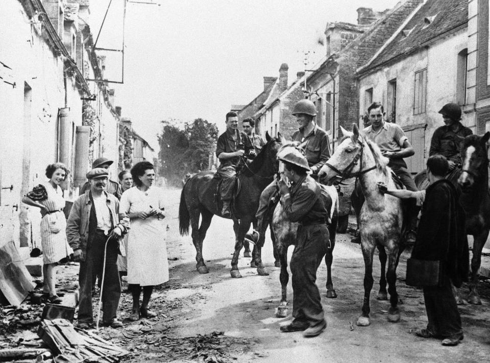 FILE - In this Aug. 30, 1944 file photo, American soldiers ride horses captured from the retreating Germans are met by town residents as they enter the French town of Chambois, Normandy, France. D-Day marked only the beginning of the Allied struggle to wrest Europe from the Nazis. A commemoration Tuesday, June 4, 2019 served as a reminder of this, in the shadow of bigger D-Day 75th anniversary commemorations. (AP Photo, File)