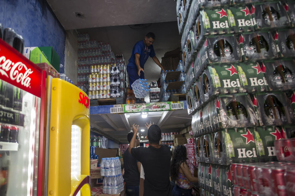 Workers toss down bottled water to be distributed in supermarkets in Rio de Janeiro, Brazil, Wednesday, Jan. 15, 2020. There’s a creeping sense of alarm in Rio de Janeiro after more than a week of foul tasting and smelling tap water in dozens of neighborhoods, and residents are hoarding bottled water. (AP Photo/Bruna Prado)