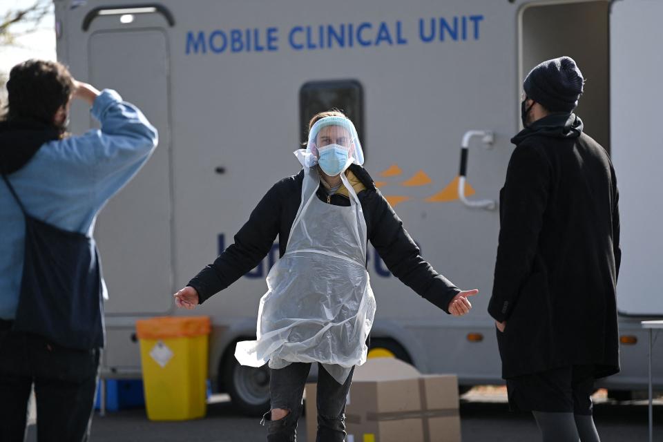 A worker dressed in PPE talks with members of the public arriving to take Covid-19 tests at a mobile testing centre in Brockwell Park (AFP via Getty Images)