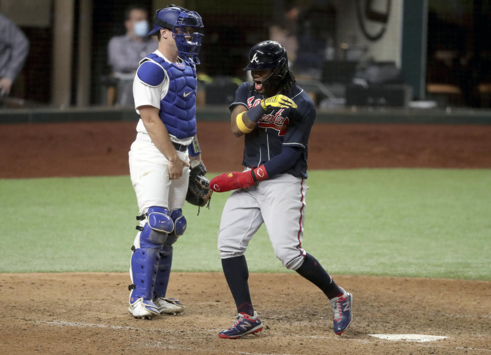 Atlanta Braves' Ronald Acuna reacts after scoring a run off of a single by designated hitter Marcell Ozuna as Los Angeles Dodgers catcher Will Smith (16) watches during the ninth inning of Game 1 of a baseball National League Championship Series, Monday, Oct. 12, 2020, in Arlington, Texas. (Curtis Compton/Atlanta Journal-Constitution via AP)