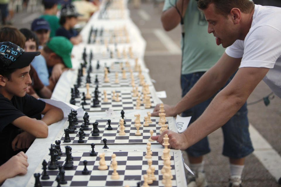 Israeli grandmaster Alik Gershon (R) looks at a board during a simultaneous chess game at Rabin Square in Tel Aviv October 21, 2010. According to the organisers, Gershon played against 525 opponents on Thursday in an attempt to break the Guinness World Record for simultaneous chess games, currently held by an Iranian. In order to set the world record, Gershon needs to win at least 80 percent of the games. REUTERS/Nir Elias