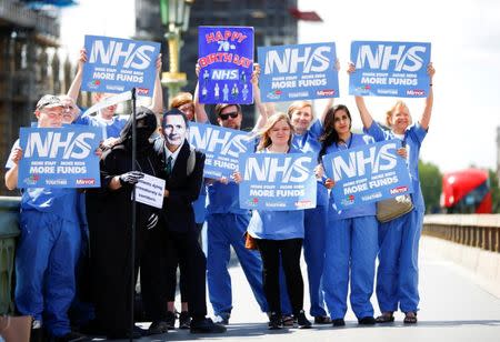 NHS staff hold banners and placards during a posed protest in central London, June 21, 2018. REUTERS/Henry Nicholls/Files