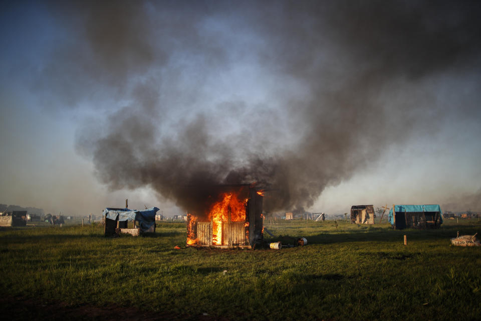 A shack home burns as people are evicted from a squatters camp by police in Guernica, Buenos Aires province, Argentina, Thursday, Oct. 29, 2020. A court ordered the eviction of families who have been squatting at the camp since July, but the families say they have nowhere to go amid the COVID-19 pandemic. (AP Photo/Natacha Pisarenko)