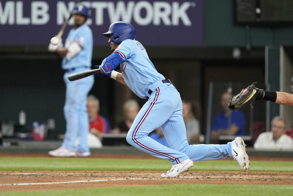 Texas Rangers' Bubba Thompson bunts the ball advancing Leody Taveras to second base against the Oakland Athletics during the fourth inning of a baseball game, Sunday, April 23, 2023, in Arlington, Texas. Bubba Thompson was out at first base. (AP Photo/Jim Cowsert)