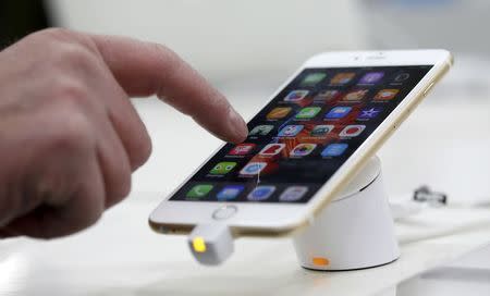 A man tests a mobile phone, an iPhone 6 by Apple in a shop in Munich, Germany, January 27, 2016. REUTERS/Michaela Rehle