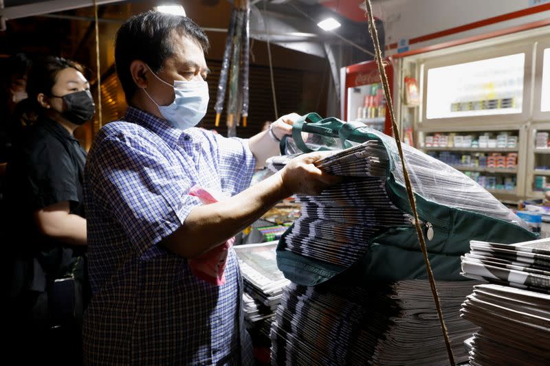 A vendor sells 100 copies of the Apple Daily newspaper to a supporter after the news organisation looked set to close for good by Saturday following police raids and the arrest of executives in Hong Kong