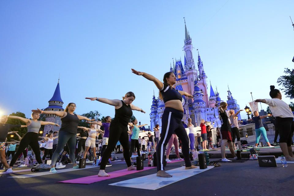 Nearly 2,000 Cast Members practice sunrise yoga celebrating International Yoga Day in front of Cinderella Castle at the Magic Kingdom Park at Walt Disney World Tuesday, June 21, 2022, in Lake Buena Vista, Fla. (AP Photo/John Raoux)