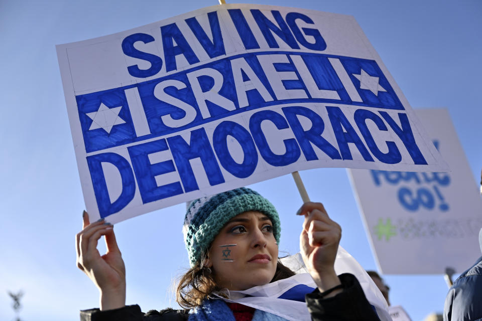 People protest with a sign, reading "saving Israeli democracy" in front of the Brandenburg Gate at a demonstration against Israel's Prime Minister Benjamin Netanyahu who is on a visit in Berlin, Germany, Thursday, March 16, 2023. (AP Photo/Steffi Loos)