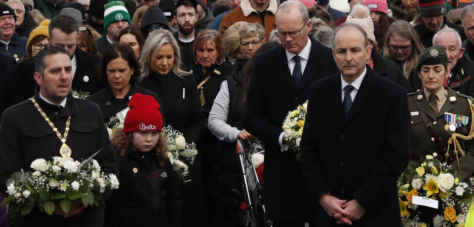 The Irish Prime Minister Micheal Martin, second right, pays his respects as people take part in a march to commemorate the 50th anniversary of the 'Bloody Sunday' shootings with the front rank holding photographs of some of the victims in Londonderry, Sunday, Jan. 30, 2022. In 1972 British soldiers shot 28 unarmed civilians at a civil rights march, killing 13 on what is known as Bloody Sunday or the Bogside Massacre. Sunday marks the 50th anniversary of the shootings in the Bogside area of Londonderry .(AP Photo/Peter Morrison)