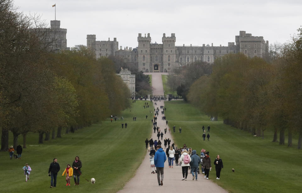 People stroll on The Long Walk towards Windsor Castle in Windsor, England, Saturday, April 10, 2021. Britain's Prince Philip, the irascible and tough-minded husband of Queen Elizabeth II who spent more than seven decades supporting his wife in a role that mostly defined his life, died on Friday. (AP Photo/Frank Augstein)