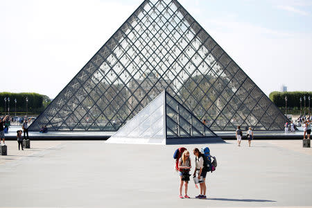 FILE PHOTO: Tourists stand in front of the Louvre Pyramid designed by Chinese-born U.S. Architect Ieoh Ming Pei in Paris, France, September 13, 2016. REUTERS/Charles Platiau/Files