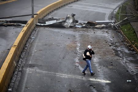 Un residente camina en medio de la barricada luego de días de protestas contra el presidente venezolano Nicolás Maduro en la ciudad de Los Teques, cerca de Caracas, Venezuela, 19 de mayo de 2017. REUTERS/Carlos Barria