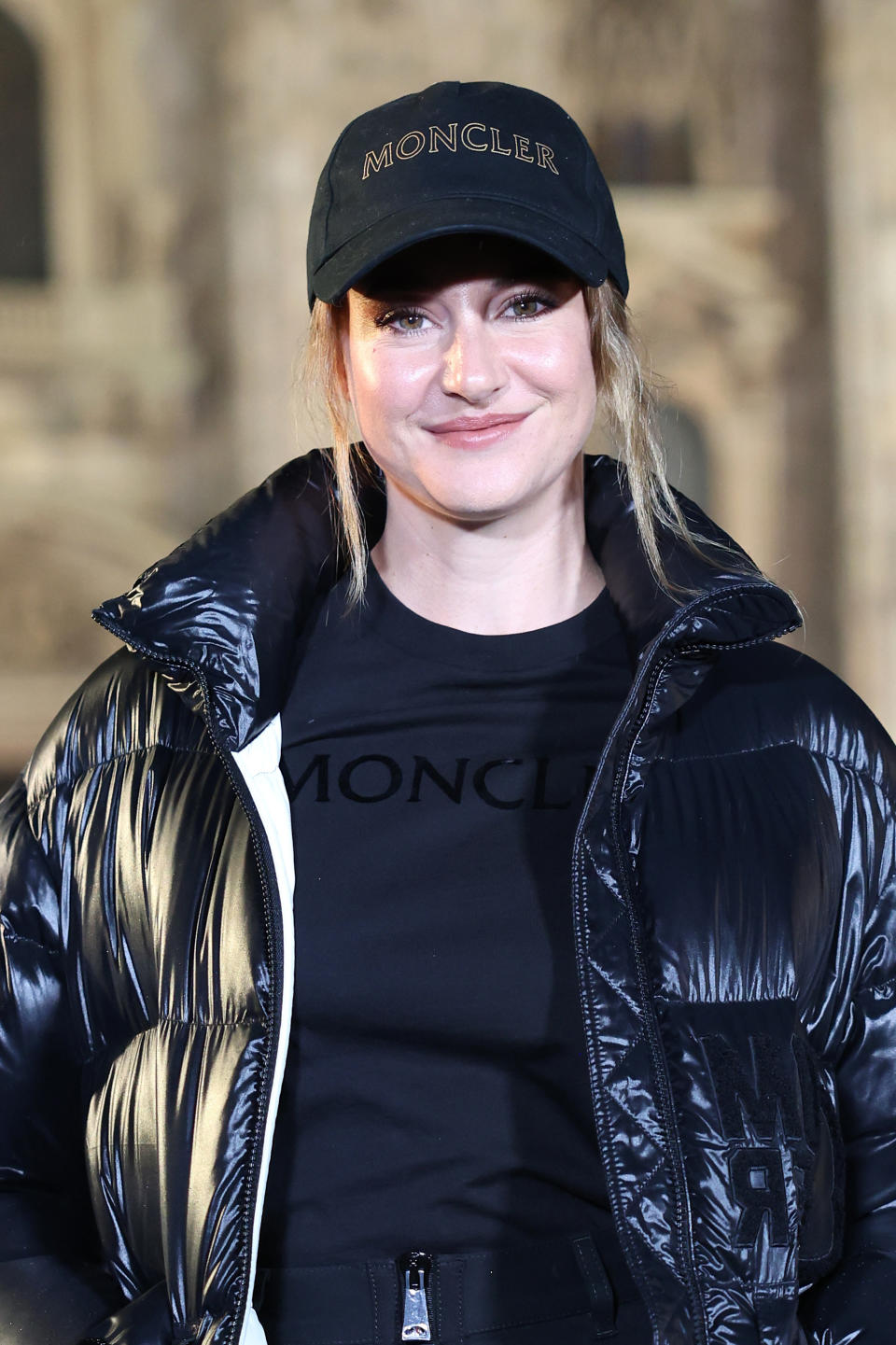 Shailene smiles as she wearing a a baseball cap and t-shirt which are both embossed with the brand name Moncler. She's also wearing a puffer jacket