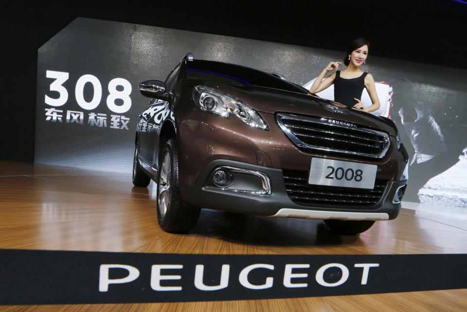 In this Nov. 21, 2013 photo, a model poses besides a Peugeot 2008 in front of the screen reads "Dongfeng Peugeot" at the company's booth during Guangzhou 2013 Auto Show in China's southern city of Guangzhou. Chinese automaker Dongfeng said Wednesday, Feb. 19, 2014 it will invest 800 million ($1.1 billion) in France’s Peugeot and expand cooperation in China’s fast-growing market. (AP Photo/Kin Cheung)